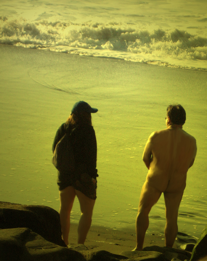 Nude man standing facing ocean on Baker's Beach in San Francisco